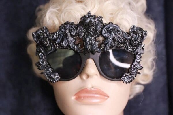 A mannequin wearing sunglasses with ornate design.