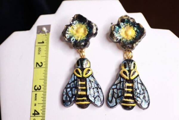 A pair of earrings with a bee and flower design.