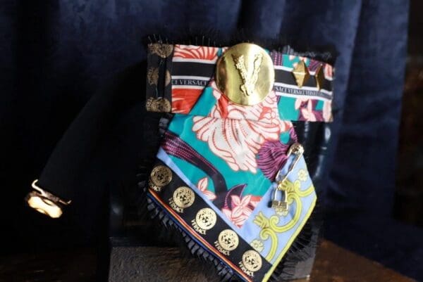 A colorful scarf with gold accents on top of it.