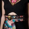 A woman wearing a colorful belt and a black dress.