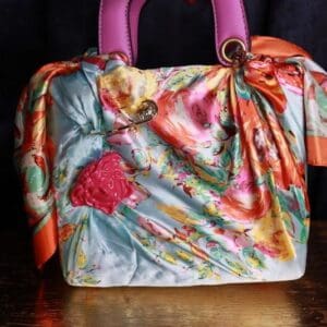 A colorful purse with a pink handle and some flowers