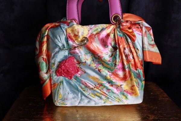 A colorful purse with a pink handle and some flowers