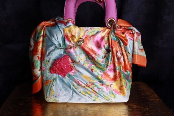 A colorful purse with a pink handle and a floral print.