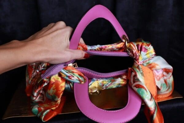 A pink toilet seat with a scarf around it.