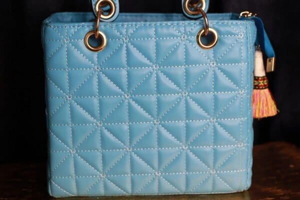 A close up of the handle on a blue purse
