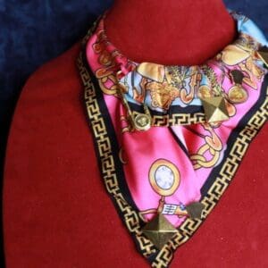 A pink and black scarf with gold trim