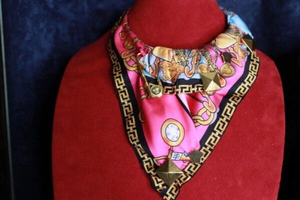 A pink and black scarf with gold trim