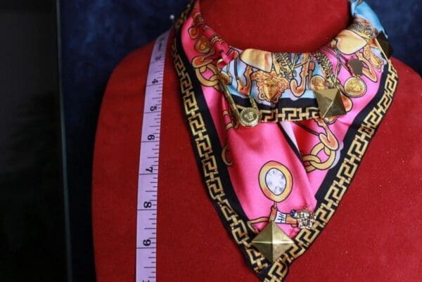 A red mannequin wearing a pink and gold neck tie.