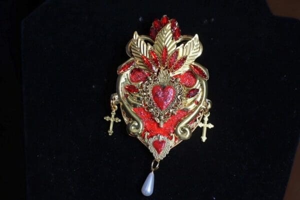 A red and gold heart with crosses hanging from it.
