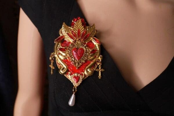A woman wearing a red and gold brooch.