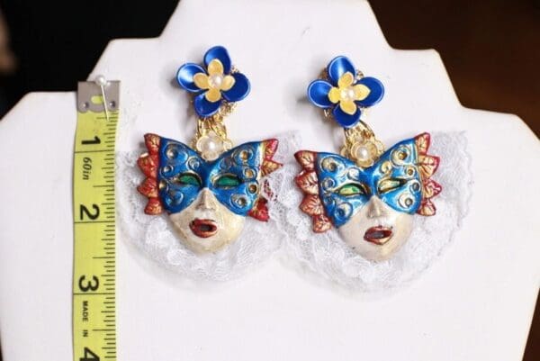 A pair of earrings with blue and red masks on them.