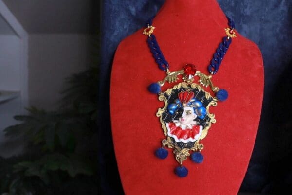 A red and blue necklace with a clown face on it.