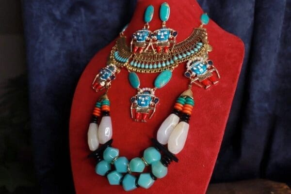 A red necklace with turquoise and other jewelry on it.