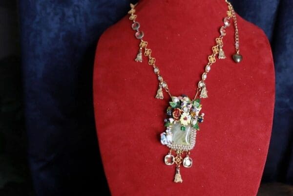 A red necklace with a green and white flower pendant.