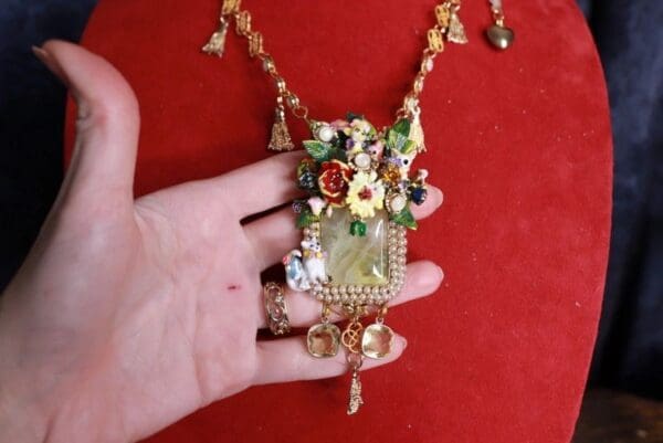 A hand holding onto a necklace with flowers