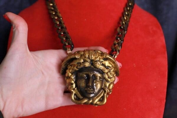 A person holding onto a chain with a medusa head on it