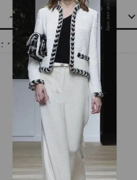 A woman in white pants and jacket on the runway.