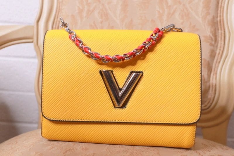 A yellow purse with the letter v on it.