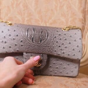 A person is holding onto the strap of a purse.