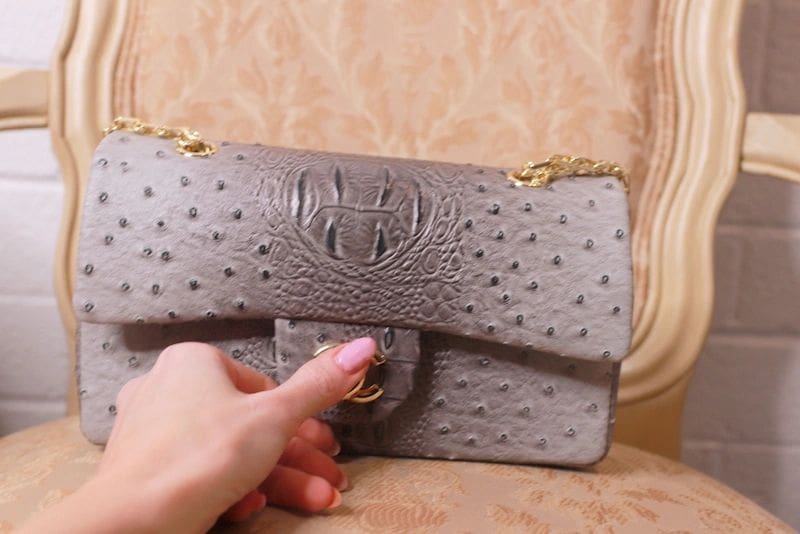 A person is holding onto the strap of a purse.