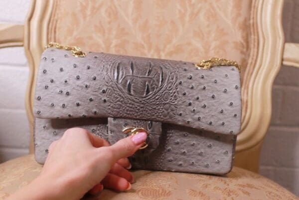 A person is holding onto the strap of a purse.