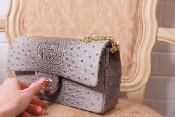 A person is holding onto the strap of a purse.