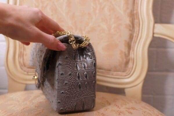 A person holding onto the handle of a purse.