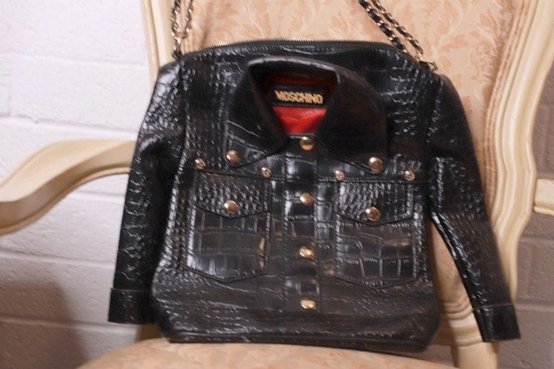 A black leather jacket with gold buttons and chain straps.