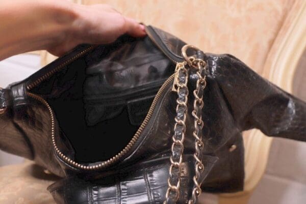 A person holding onto the chain of their purse