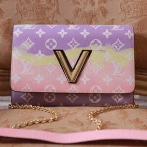 A pink, purple and yellow louis vuitton bag sitting on top of a table.