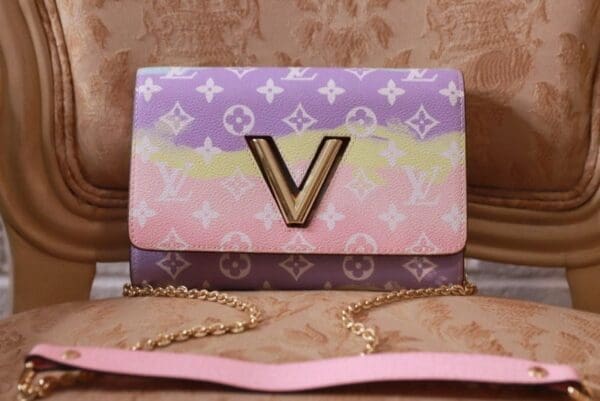 A pink, purple and yellow louis vuitton bag sitting on top of a table.