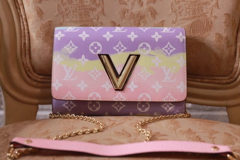 A pink, purple and yellow louis vuitton bag sitting on top of a table.