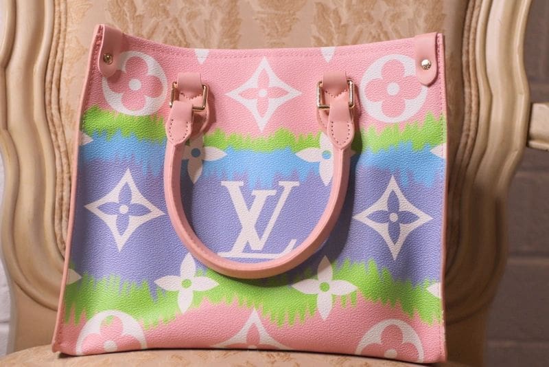 A pink, blue and green louis vuitton bag sitting on top of a table.