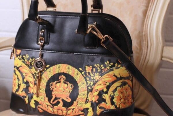 A black purse with yellow and orange designs on it.