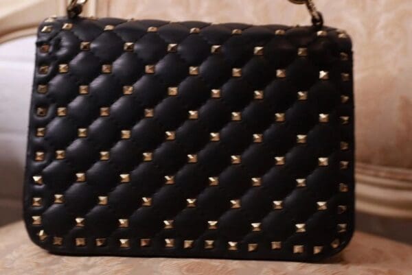 A black purse with gold studs on it.
