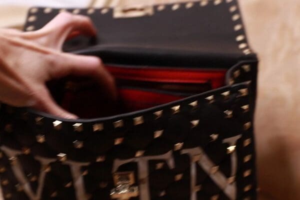 A person holding onto the inside of a purse.