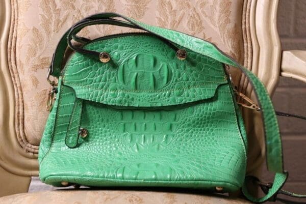 A green purse sitting on top of a bed.