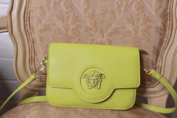 A yellow purse with a gold chain strap.
