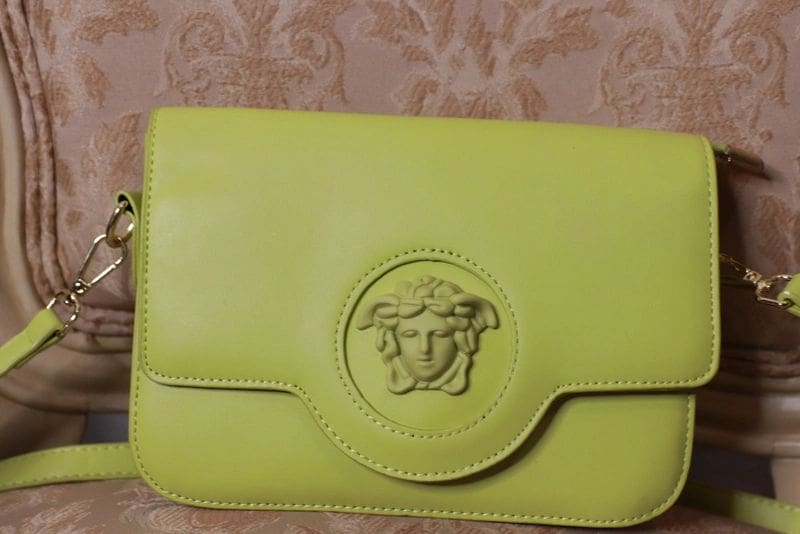 A lime green purse with a medusa head on the front.