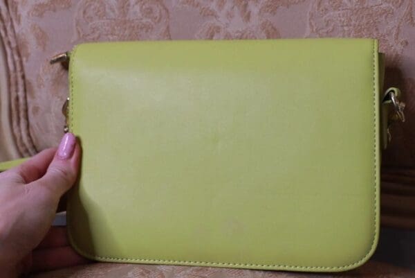 A person holding onto the side of a yellow wallet