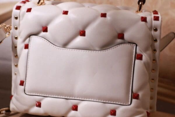 A white purse with red accents on it.