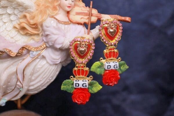A pair of earrings with roses and hearts on them.