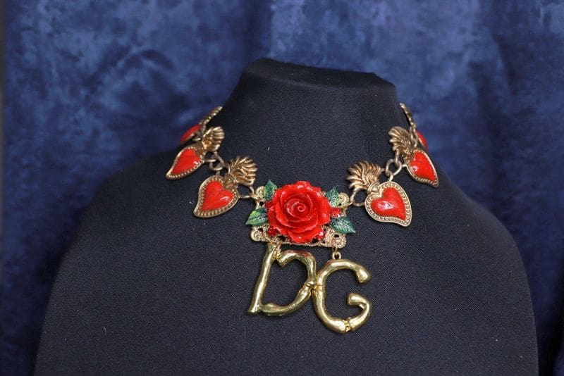 A necklace with a red rose and leaves on it.