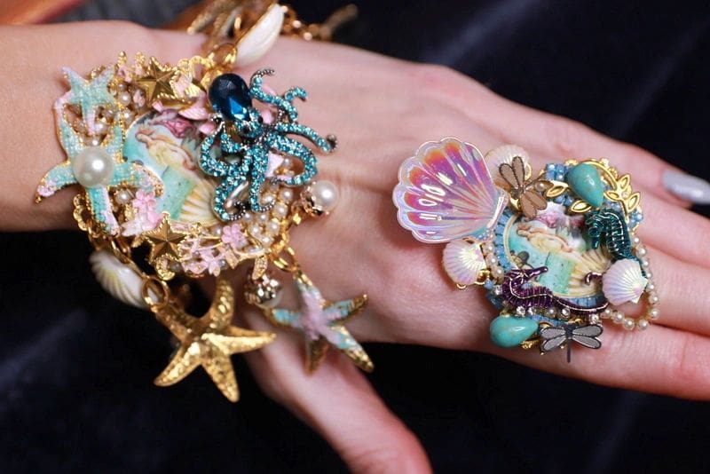 A hand with many different jewelry on it