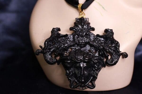 A black necklace with a large cross shaped pendant.