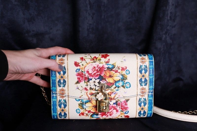 A person holding onto a floral purse