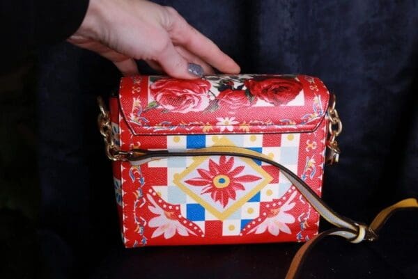 A hand is holding onto the handle of a purse.