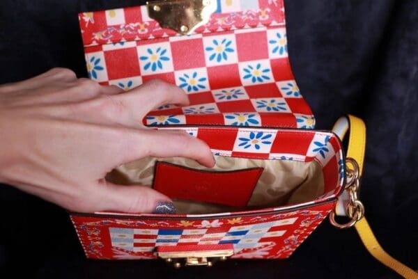 A person opening up a red purse with blue and white checkered design.