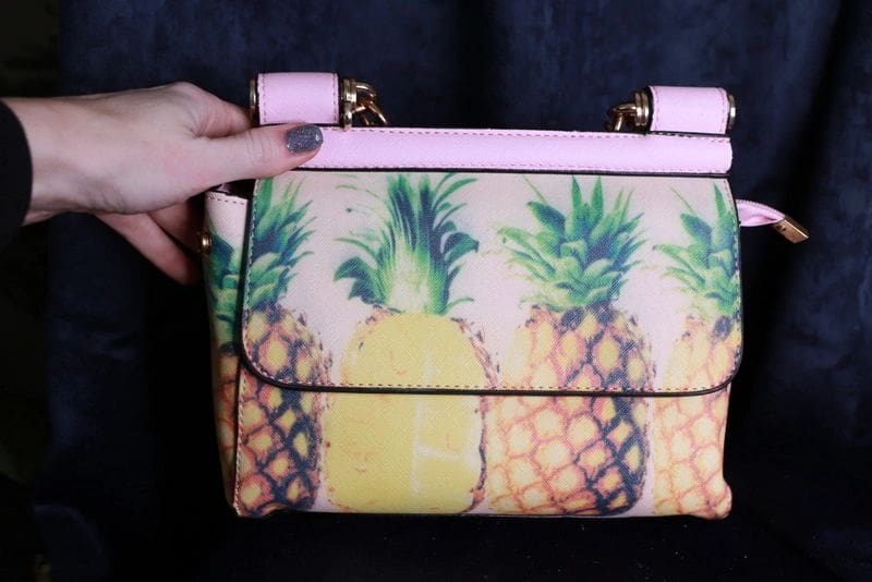 A person holding onto a pineapple purse