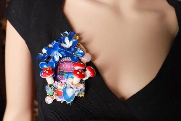 A woman wearing a brooch with flowers and mushrooms.